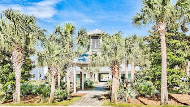A building with a central dome and a covered walkway surrounded by palm trees.