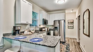 A modern kitchen with white cabinets, a granite countertop, and stainless steel appliances.