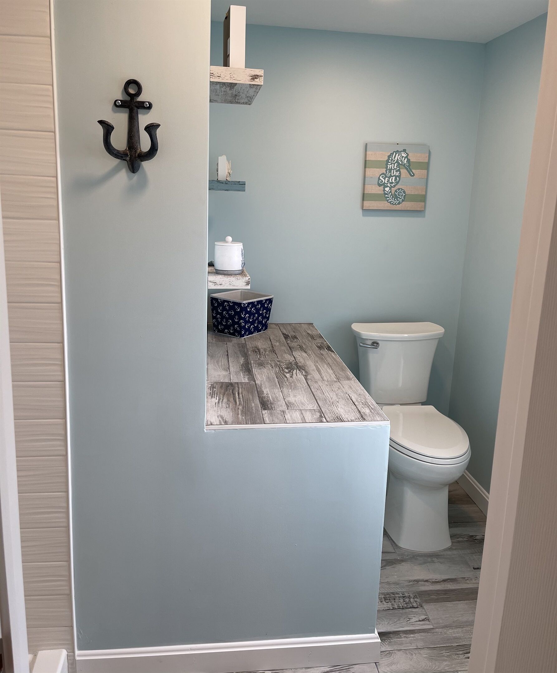 A bathroom with a wooden vanity, a toilet, and a wall-mounted shelf with a decorative item.