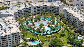 A multi-story hotel with a central pool area surrounded by balconies and palm trees.