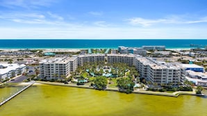 A high-rise hotel with multiple balconies, a central pool, and a view of the beach and ocean. - Stunning Coastal Condo | Private Beach & Water Views | Daily VIP Excursions (Fort Walton Beach)