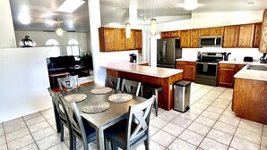 A modern kitchen with wooden cabinets, a central island, and a dining area with a table and chairs. - Spacious Prescott Home w/Fenced Yard & Central Loc (Prescott)