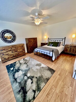 A bedroom with a bed, wooden dresser, nightstands, a ceiling fan, and a round mirror. - Spacious Prescott Home w/Fenced Yard & Central Loc (Prescott)