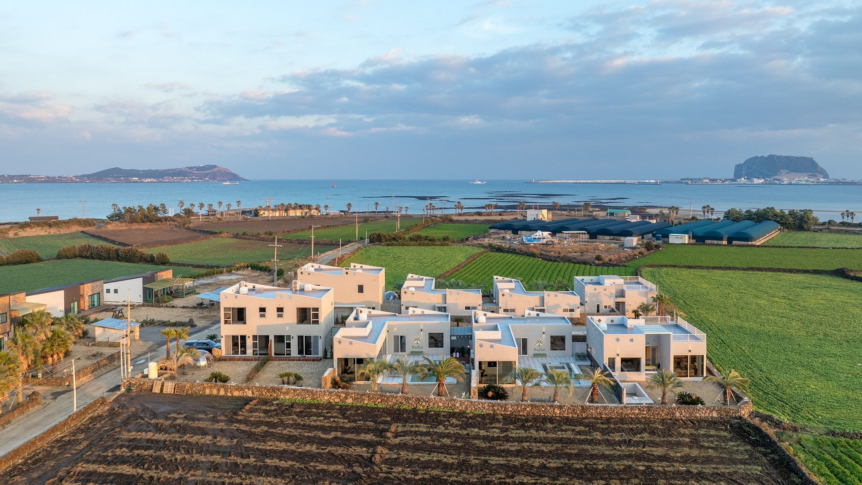 Une zone résidentielle côtière comprenant des maisons modernes, un port de plaisance et des terres agricoles.