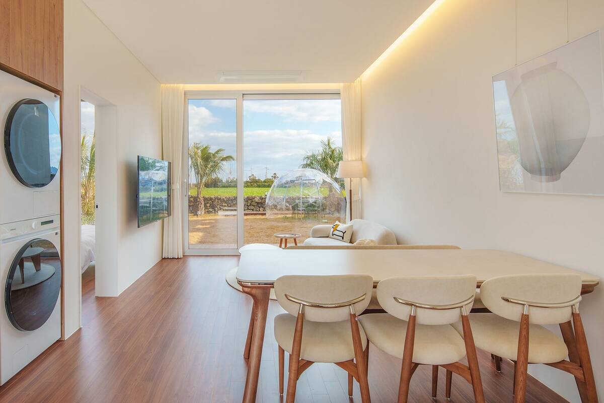 A modern room with a dining area, a TV, and a view of the outdoors.