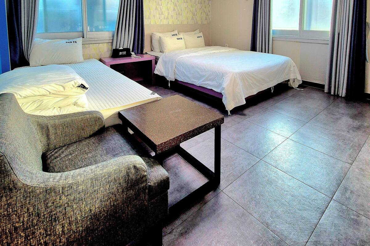 A hotel room with two beds, a desk, and a window with curtains.