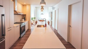A modern kitchen with a central island, built-in appliances, and pendant lighting. - Terminus Hôtel (Québec)