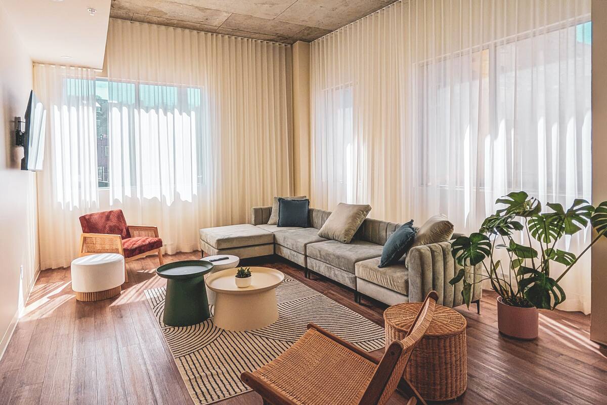 Uma sala de estar espaçosa com um amplo sofá de canto, uma mesa de centro redonda e uma planta em vaso.