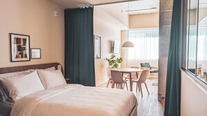 A hotel room with a bed, a dining table with chairs, a potted plant, and a view of the balcony. - Terminus Hôtel (Québec)