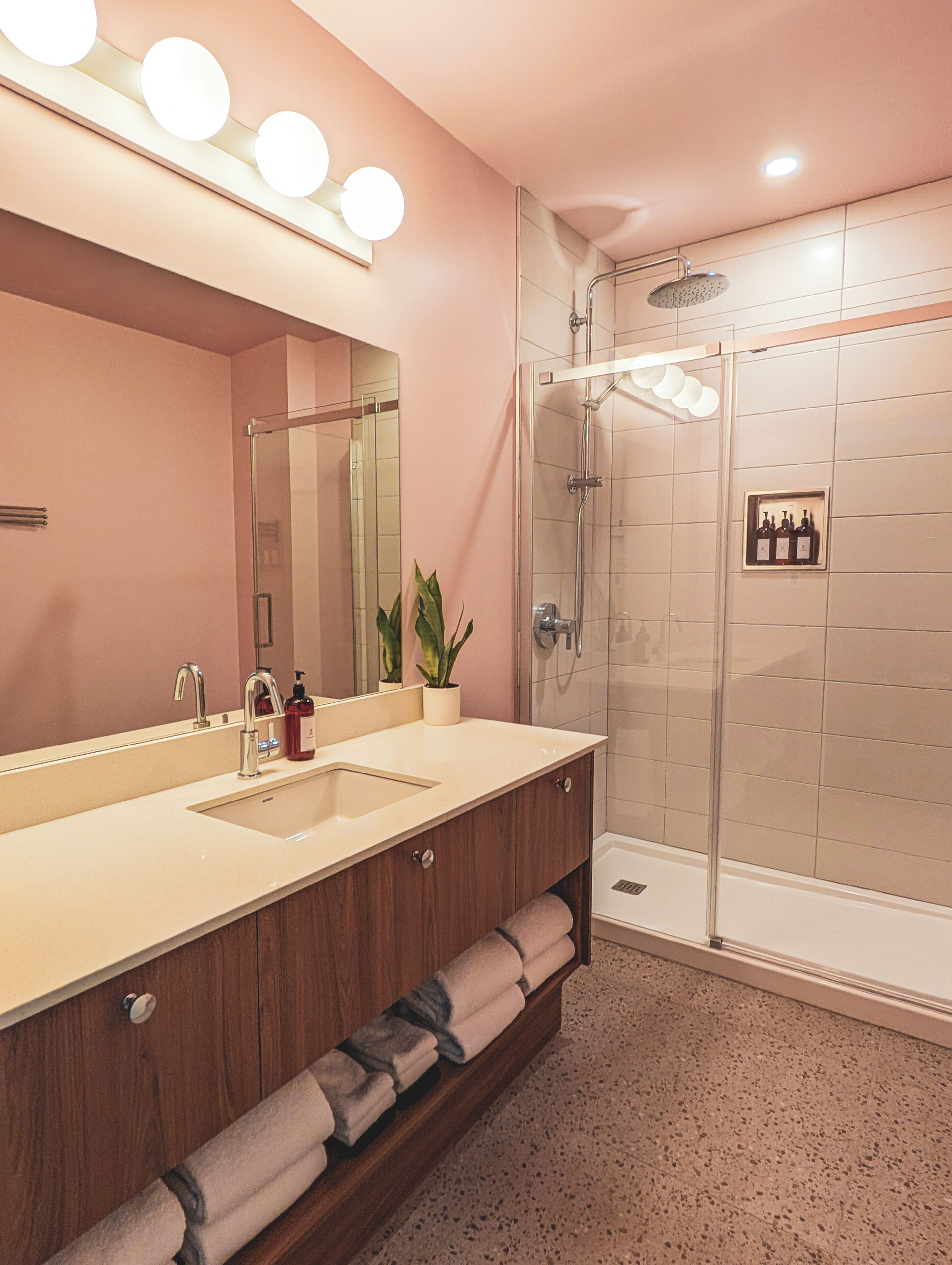 A modern bathroom with a dual sink vanity, a large mirror, and a glass-enclosed shower.