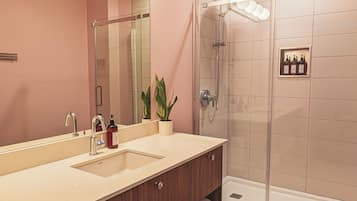 A modern bathroom with a dual sink vanity, a large mirror, and a glass-enclosed shower.
