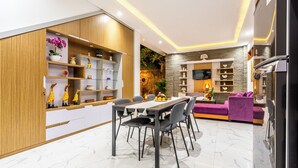 Ein modernes Wohnzimmer mit Essbereich, ausgestattet mit einem Holzkabinett mit Regalen, einer Couch und einem Fernseher.