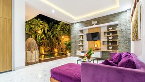 Ein modernes Wohnzimmer mit einem violetten Sofa, einem Flachbildfernseher und einer Wand mit Steinoptik.