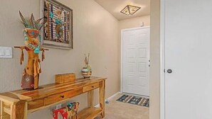 A hallway with a wooden bench, a framed artwork, and a white door. - Cozy and convenient Condo (Mesa)