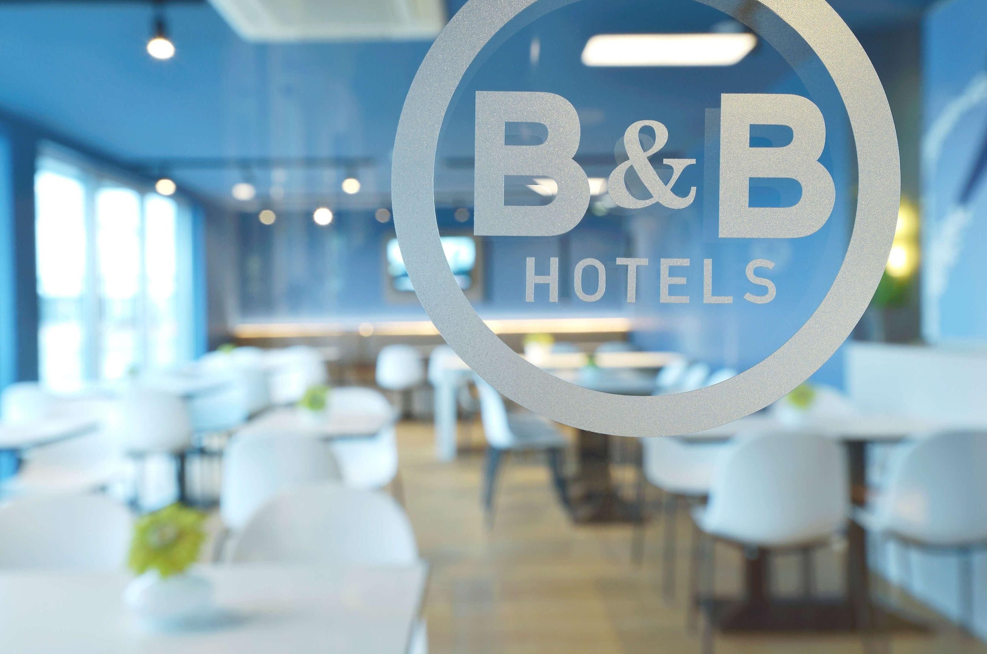 Interior de un hotel B&B con diseño moderno, que presenta un logotipo circular en un panel de vidrio.