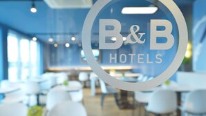 Interior de un hotel B&B con diseño moderno, que presenta un logotipo circular en un panel de vidrio.