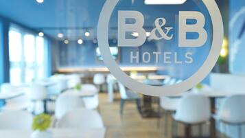 Interior de un hotel B&B con diseño moderno, que presenta un logotipo circular en un panel de vidrio.