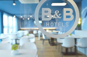 Interior de un hotel B&B con diseño moderno, que presenta un logotipo circular en un panel de vidrio.
