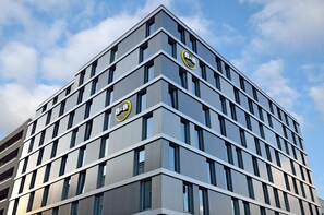 Edifici d'hotel modern amb una estructura de finestres i dos senyals destacats que indiquen que és un albergueta.