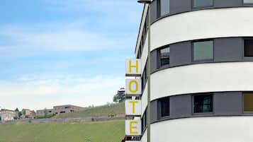 Señal de hotel en un edificio moderno con vistas a viñedos al fondo.