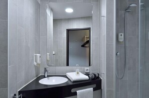 Un baño moderno con un espejo grande, un lavabo, una toalla y una zona de ducha.