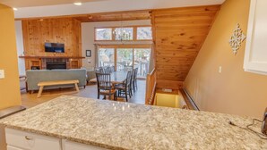 A kitchen with granite countertops, a dining area with a table and chairs, a fireplace, and a view of the outdoors. - Large Loon Condo w/Amenities (Lincoln)