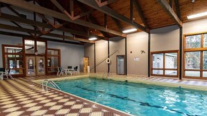 An indoor swimming pool with a checkered floor pattern, clear water, and wooden beams on the ceiling.
