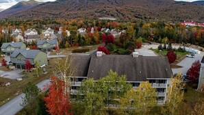 A residential area with houses, a large building with a flat roof, and a mountainous backdrop.