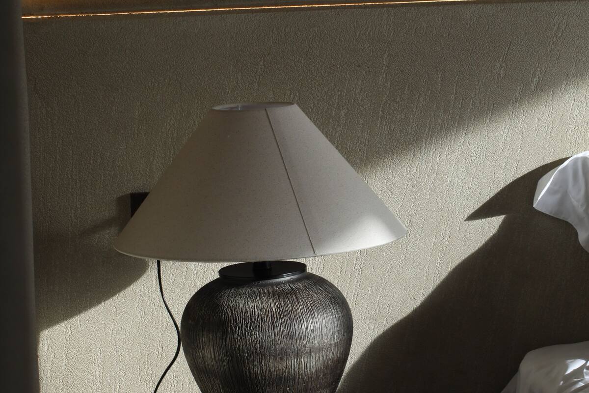 Una lámpara sobre una mesita de noche en una habitación de hotel.