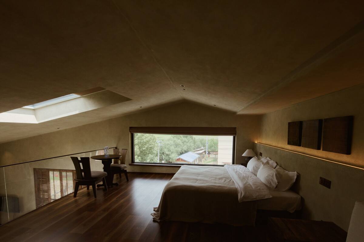 Un dormitorio con tragaluz, una cama, un escritorio y una silla.