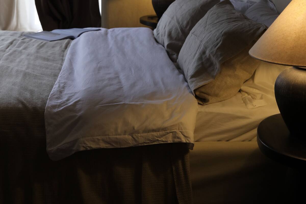 Una habitación de hotel con cama, dos lámparas de noche y ventana con cortinas.