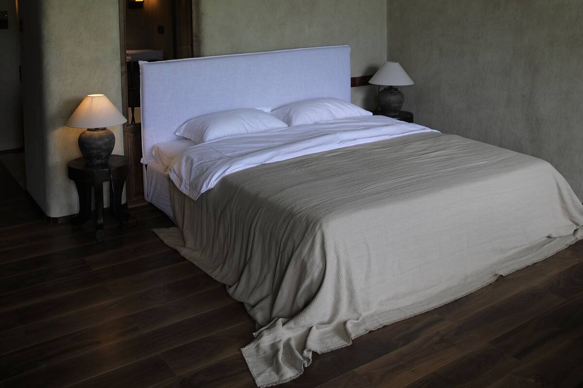 Un dormitorio con una cama grande, una mesita de noche, una lámpara y un tragaluz.
