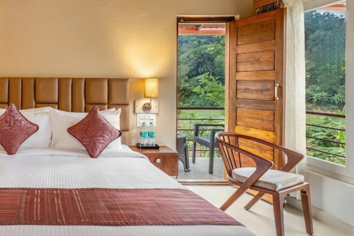 Ein Hotelzimmer mit einem großen Bett, einem Holzkopfende, Nachttischen mit Lampen, einem Schreibtisch und einem Stuhl.