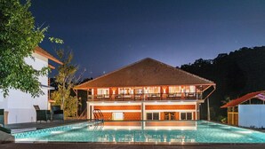 Un edificio a due piani con una piscina di fronte.