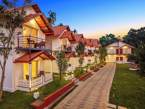 Una hilera de villas modernas de dos plantas con techos de tejas rojas, balcones y un jardín bien cuidado.
