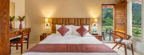A hotel room with a large bed, wooden headboard, bedside tables with lamps, a desk, and a chair.