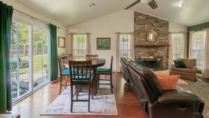 A spacious living room with a fireplace, a dining area, and a large window overlooking a backyard. - 10 Min. Drive From Tournament! WiFi, Parking for 3! Fire Pit! TV's In All Rooms! (Martinez)