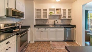 A modern kitchen with white cabinets, stainless steel appliances, and a tiled backsplash. - 10 Min. Drive From Tournament! WiFi, Parking for 3! Fire Pit! TV's In All Rooms! (Martinez)