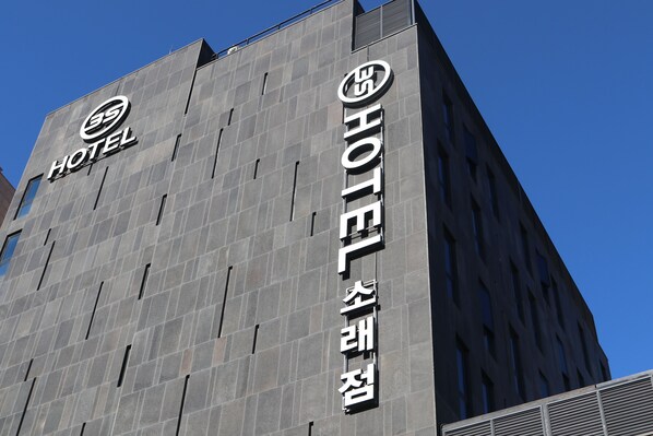 A modern hotel building with a prominent sign reading "HOTEL" and "HOTEL" in another language.
