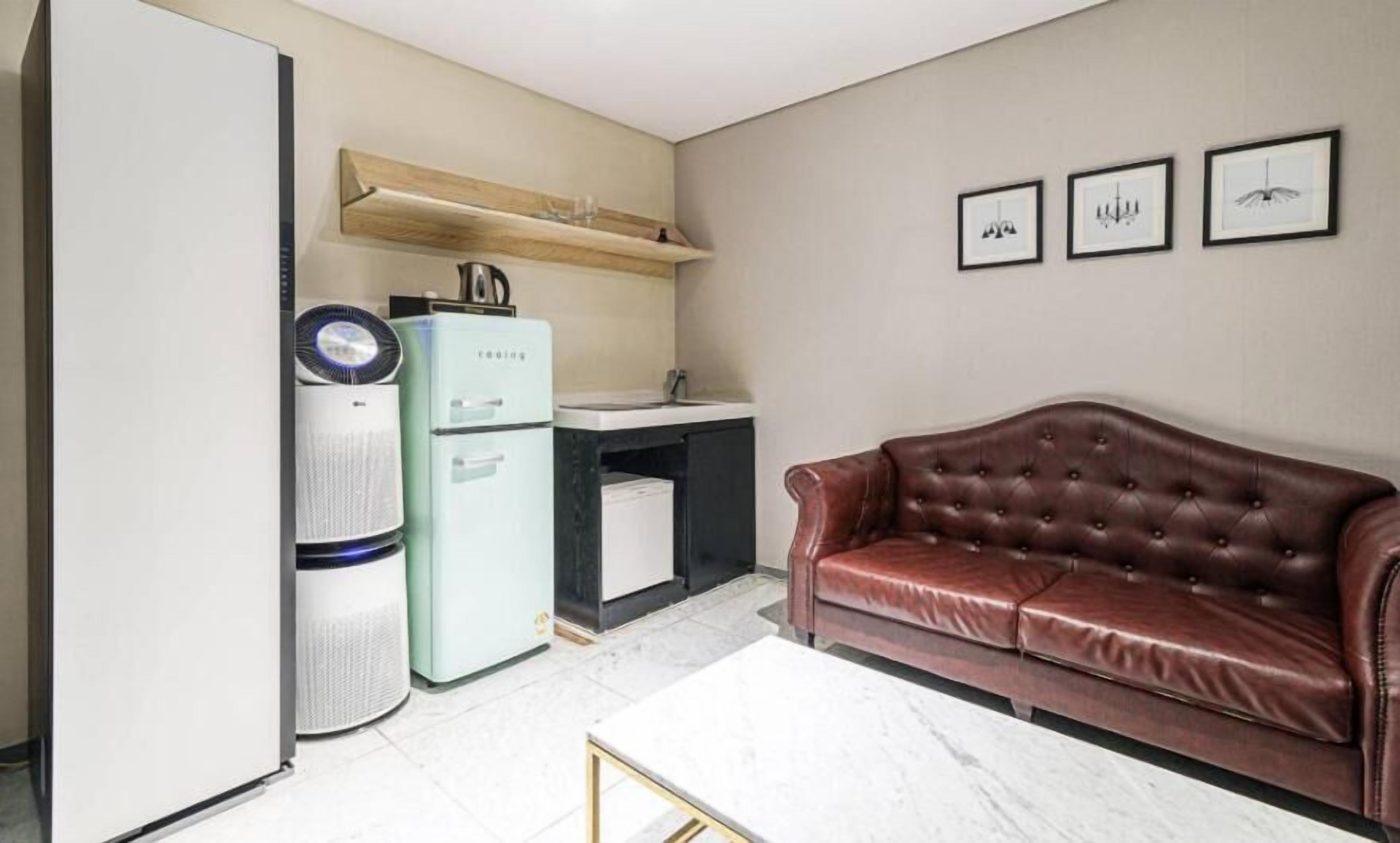 A compact living space with a kitchenette, a brown leather sofa, and a small dining table.