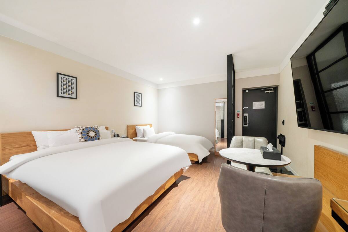 A hotel room with a large bed, a smaller bed, a round table, and a seating area.