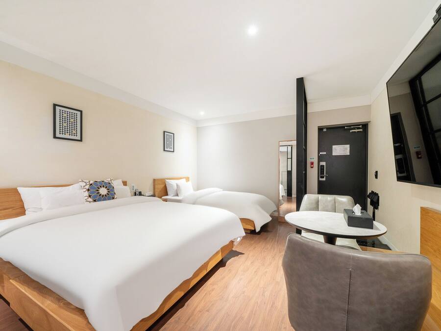 Une chambre d’hôtel avec un grand lit, un lit plus petit, une table ronde et un coin salon.