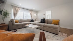 A modern living room with a sectional sofa, a coffee table, and a potted plant. - Serene river view & beach walk, near Monterey Aquarium, Laguna Seca, Santa Cruz (Moss Landing)