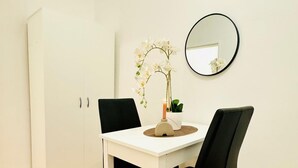 Une table blanche avec une bougie, une plante en pot et un miroir accroché au mur.