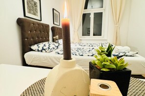 Une chambre avec un lit, une table de chevet sur laquelle se trouve une bougie et une plante en pot.