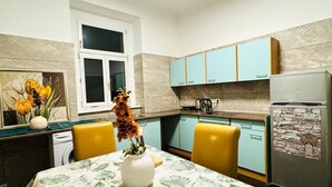 A kitchen with light blue cabinets, a white refrigerator, and a dining table with yellow chairs.