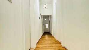 A long, narrow hallway with wooden flooring and white walls.