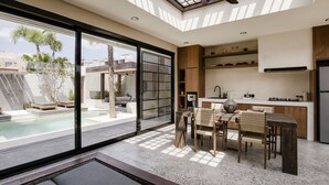 Cozinha moderna com uma ilha grande, área de jantar com mesa e cadeiras, e vista para uma piscina.