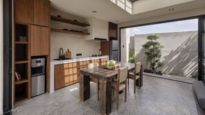 Cozinha moderna com armários de madeira, uma ilha central e um espaço de refeições com mesa e cadeiras.