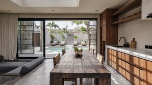 Cozinha moderna com mesa de madeira, forno embutido e uma grande janela com vista para uma área de piscina.